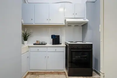 a kitchen with white cabinets and a black oven at Cozy 1 BR Apt in Koukaki in Athens