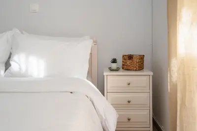 a bedroom with a white bed and a night stand at Cozy 1 BR Apt in Koukaki in Athens
