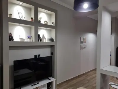 a living room with a flat screen tv and shelves at Stylish Fully Renovated Apartment - Koukaki in Athens