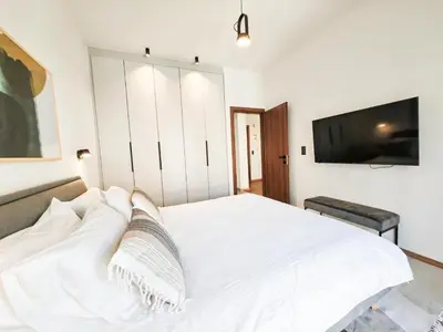 a bedroom with a white bed and a flat screen tv at Ako 25 - stay close to the Acropolis in Athens