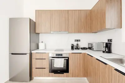 a kitchen with white appliances and wooden cabinets at Ako 25 - stay close to the Acropolis in Athens