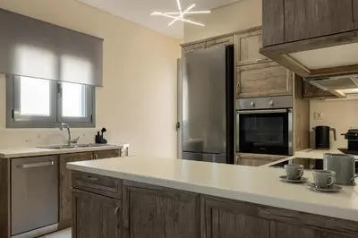 a kitchen with wooden cabinets and a stainless steel refrigerator at Saronida Hilltop Sea Breeze in Saronida