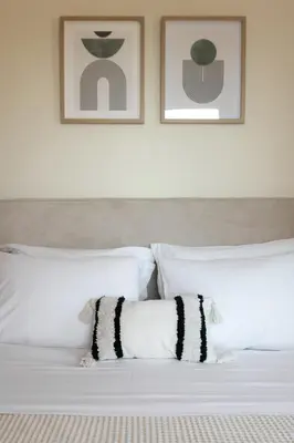 a bed with white pillows and two pictures on the wall at Saronida Hilltop Sea Breeze in Saronida