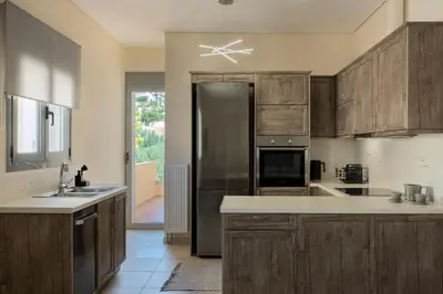 a kitchen with wooden cabinets and a stainless steel refrigerator at Saronida Hilltop Sea Breeze in Saronida