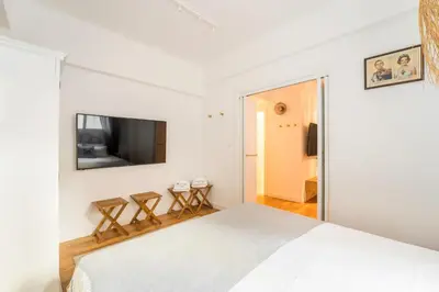 a white bedroom with a bed and a flat screen tv at Athenian Thiseos in Athens