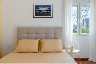 a white bedroom with a bed with a large window at Serenity Apartments in Athens