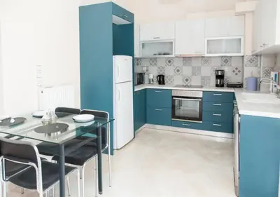 a kitchen with blue cabinets and a table and chairs at ZenPort in Piraeus
