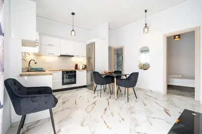 a kitchen with white cabinets and a table and chairs at Elegant Apartment in Glyfada 2 Bdrms by MPS in Athens