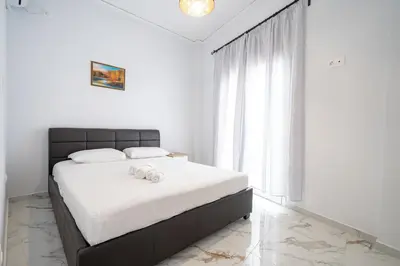 a bedroom with a bed with white sheets and a window at Elegant Apartment in Glyfada 2 Bdrms by MPS in Athens