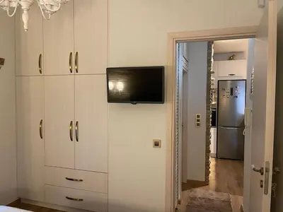a kitchen with white cabinets and a tv on the wall at Brick house in Athens