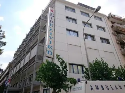 a large white building with a sign on it at Little house in the city in Athens
