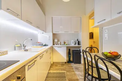 a kitchen with white cabinets and a table and chairs at Little house in the city in Athens