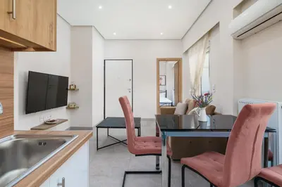 a kitchen and living room with a table and pink chairs at Modern Apartment Nearby Acropolis & Metro in Athens
