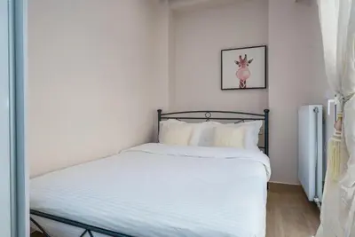 a bedroom with a bed with white sheets and a refrigerator at Modern Apartment Nearby Acropolis & Metro in Athens