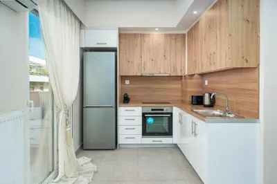 a kitchen with wooden cabinets and a refrigerator at Modern Apartment Nearby Acropolis & Metro in Athens