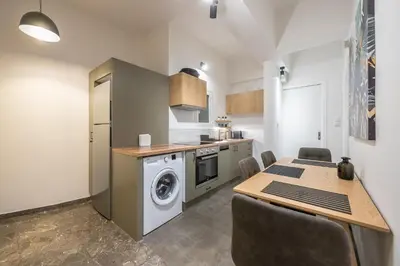 a kitchen with a washing machine and a table with chairs at Airy 1BR by Flisvos Marina in Athens