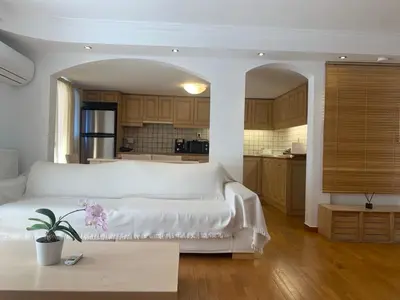a living room with a white bed and a kitchen at Dafni Athens loft in Athens