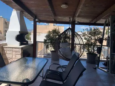 a porch with a swing and a table and chairs at Dafni Athens loft in Athens