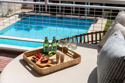 a tray of food and wine glasses on a table next to a pool at 1BD SV Beach Condo with Pool in Athens