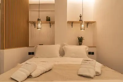 a bed with white sheets and pillows in a room at Mini Sinatra Suite Syntagma in Athens