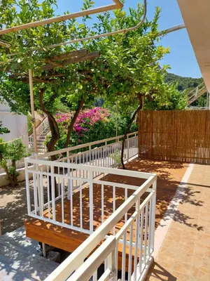 a white fence next to a tree with pink flowers at George Apartments in Aegina Town