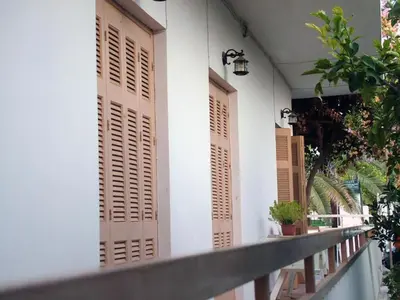 a white building with brown shutters on it at George Apartments in Aegina Town