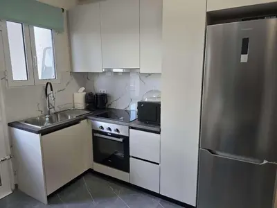 a kitchen with white cabinets and a stainless steel refrigerator at Nektaria philoxenia place in Athens