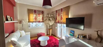a living room with a couch and a flat screen tv at Cozy Near Acropolis by LV in Athens