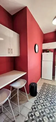 a kitchen with a red wall with a table and chairs at Cozy Near Acropolis by LV in Athens