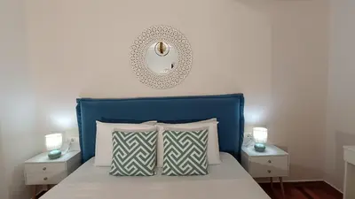 a bed with a blue headboard and a mirror on the wall at Central Apartment Near Acropoli in Athens