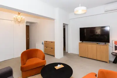 a living room with orange chairs and a flat screen tv at Horizon Haven in Athens