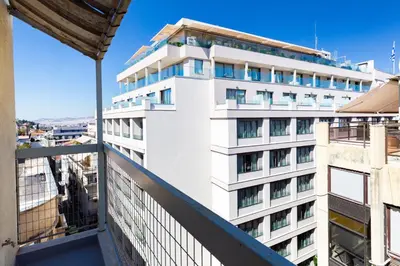 a tall white building with windows on a balcony at Horizon Haven in Athens