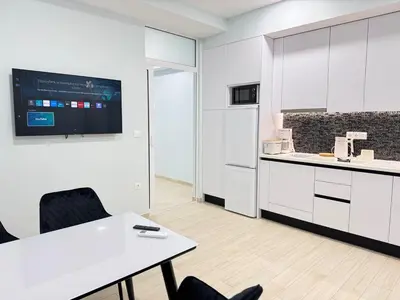 a kitchen with white cabinets and a white table and chairs at City Vibes Athens in Athens