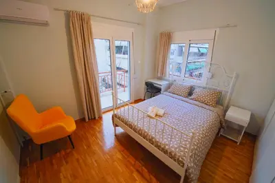 a bedroom with a bed and a chair and two windows at Cozy Central Stay in Athens