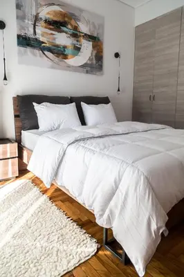 a bedroom with a large bed with white sheets and a rug at Athens Neos Kosmos 2BDR apt next to metro station in Athens