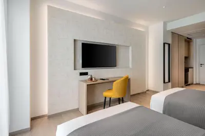 a bedroom with two beds and a desk with a television at Urban K in Athens