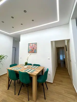 a dining room with a wooden table and green chairs at Casa Marina in Athens