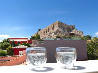 two glasses of water sitting on a table with a mountain at The Acropolis Window in Athens
