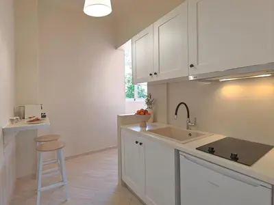 a kitchen with white cabinets and a sink and a stool at The Acropolis Window in Athens
