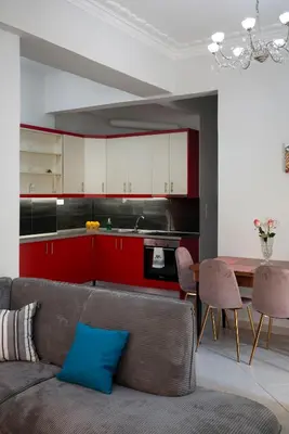 a living room with a couch and a kitchen with red cabinets at Cuka apartment 3BD nexto to metro and Piraeus Port in Piraeus