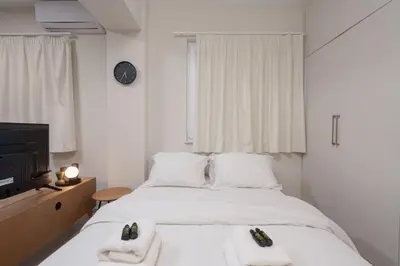 a white bedroom with two beds and a tv at Quiet Studio In The Heart of Athens in Athens