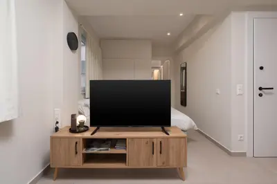 a flat screen tv on a wooden stand in a room at Quiet Studio In The Heart of Athens in Athens