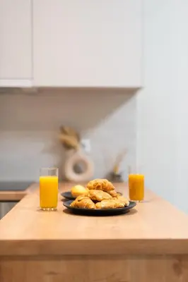 a plate of pastries on a counter with two glasses of orange juice at Quiet Studio In The Heart of Athens in Athens
