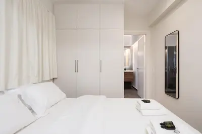 a white bedroom with a white bed and a mirror at Quiet Studio In The Heart of Athens in Athens
