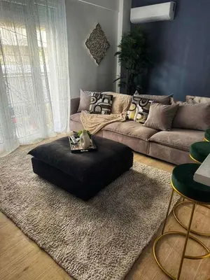 a living room with a couch and a black ottoman at Modern Athens Apartment - Close to Metro in Athens