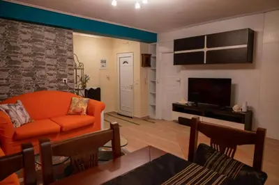 a living room with an orange couch and a television at Apartment Margarita in Athens