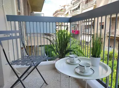 a table and a chair on a balcony with cups and saucers at Apartment Cathrine in Athens