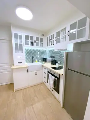 a kitchen with white cabinets and a stainless steel refrigerator at MediTerra Stay Athens Park Place in Athens