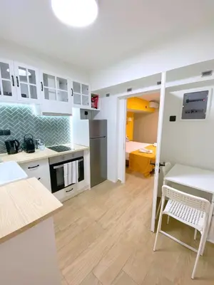 a kitchen with white cabinets and a table and a chair at MediTerra Stay Athens Park Place in Athens