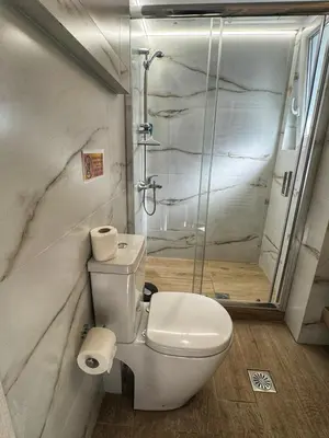 a bathroom with a toilet and a glass shower at Modern Athens Escape - Queen Bed & Metro Access in Athens